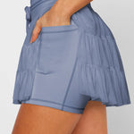 Women's slate blue ruffle workout skort with moisture-wicking fabric, high-rise drawstring waist, and built-in shorts.