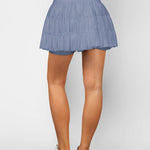 Women's slate blue ruffle workout skort with moisture-wicking fabric, high-rise drawstring waist, and built-in shorts.