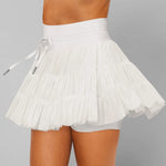 Women's white tiered ruffle sport skort featuring high-rise drawstring waist and integrated compression shorts for tennis or running.