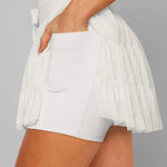 Women's white tiered ruffle sport skort featuring high-rise drawstring waist and integrated compression shorts for tennis or running.