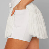 Women's white tiered ruffle sport skort featuring high-rise drawstring waist and integrated compression shorts for tennis or running.