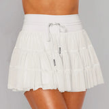 Women's white tiered ruffle sport skort featuring high-rise drawstring waist and integrated compression shorts for tennis or running.