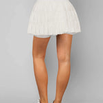 Women's white tiered ruffle sport skort featuring high-rise drawstring waist and integrated compression shorts for tennis or running.