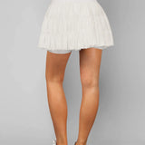 Women's white tiered ruffle sport skort featuring high-rise drawstring waist and integrated compression shorts for tennis or running.