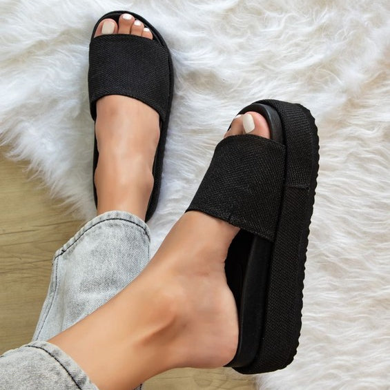Woman wearing woven raffia flatform slide sandals in black, showcasing chunky espadrille-style platform perfect for summer casual outfit.