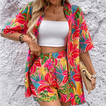 Women's tropical floral two-piece set with relaxed short-sleeve button shirt and high-waist shorts in vibrant fuchsia, coral, lime, and turquoise hibiscus print – lightweight resort outfit.