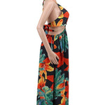 Woman wearing a vibrant tropical floral cut-out halter maxi dress with gold chain belt and thigh-high slit.