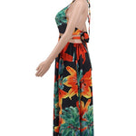 Woman wearing a vibrant tropical floral cut-out halter maxi dress with gold chain belt and thigh-high slit.