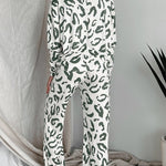 Back view of woman wearing sage green and white leopard print two-piece lounge set with long sleeves and wide-leg pants.