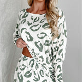 Woman standing and smiling in full-length view of sage and white animal print loungewear set, styled with sneakers and a mini handbag.