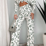 Woman standing and smiling in full-length view of sage and white animal print loungewear set, styled with sneakers and a mini handbag.