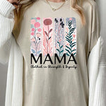 Cream-colored T-shirt with pastel pink and teal floral panel design and bold ‘MAMA’ graphic reading ‘Clothed in Strength & Dignity.