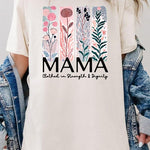 Cream-colored T-shirt with pastel pink and teal floral panel design and bold ‘MAMA’ graphic reading ‘Clothed in Strength & Dignity.