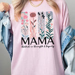 Pink T-shirt with pastel pink and teal floral panel design and bold ‘MAMA’ graphic reading ‘Clothed in Strength & Dignity.