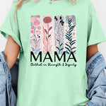 Green T-shirt with pastel pink and teal floral panel design and bold ‘MAMA’ graphic reading ‘Clothed in Strength & Dignity.