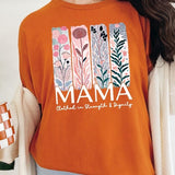 Orange T-shirt with pastel pink and teal floral panel design and bold ‘MAMA’ graphic reading ‘Clothed in Strength & Dignity.