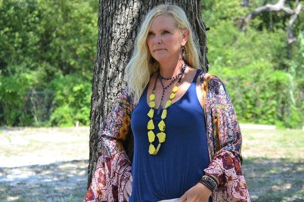 Double strand blue lapis lazuli bead necklace with natural gold and gray flecks, displayed on a light wooden surface.