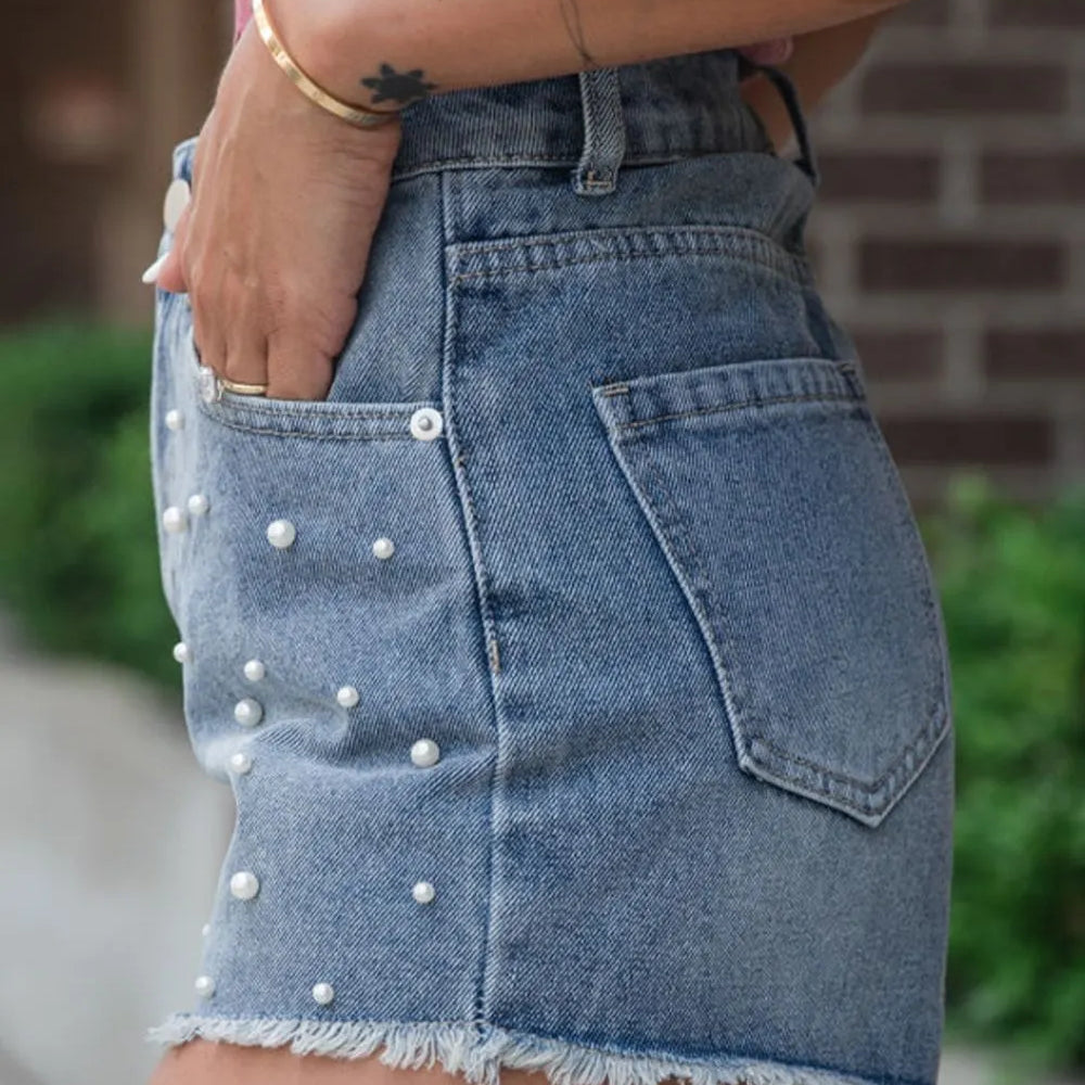 Women's high-waisted denim shorts with faux pearl embellishments and frayed hem – trendy summer jean shorts for casual and chic outfits.