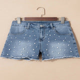 Women's high-waisted denim shorts with faux pearl embellishments and frayed hem – trendy summer jean shorts for casual and chic outfits.