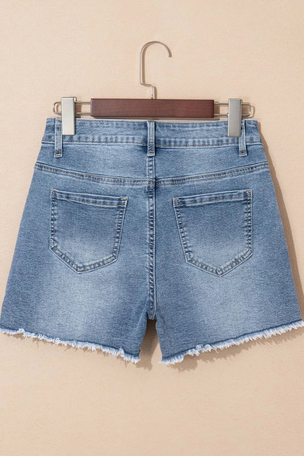 Women's high-waisted denim shorts with faux pearl embellishments and frayed hem – trendy summer jean shorts for casual and chic outfits.