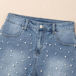 Women's high-waisted denim shorts with faux pearl embellishments and frayed hem – trendy summer jean shorts for casual and chic outfits.