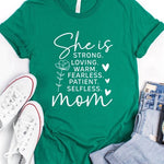 Mint Green graphic T-shirt reading ‘She is strong, loving, warm, fearless, patient, selfless—mom’ styled flat-lay with tan fedora, denim shorts, and greenery.