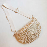 Gold and ivory woven leopard-print crossbody belt bag with adjustable ivory strap and zip closure, laid flat on a white background.