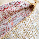 Close-up of floral interior lining with zip pocket inside a glittery woven crossbody bag featuring the Ellison + Young label.