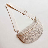 Silver and ivory woven leopard-print crossbody belt bag with ivory strap and zipper, displayed on a neutral background.